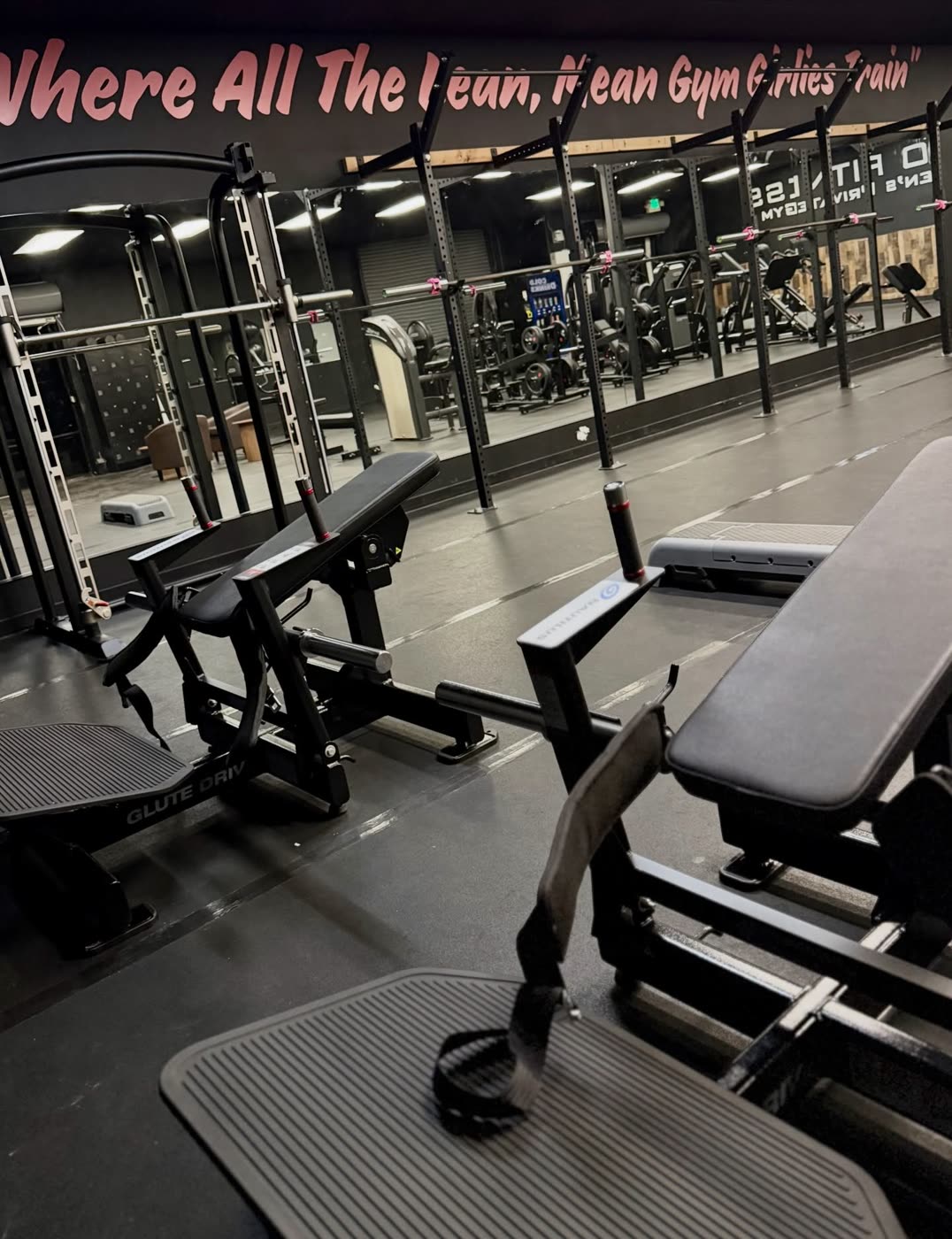 Hip thrust machine and a padded bench in front of a mirrored wall