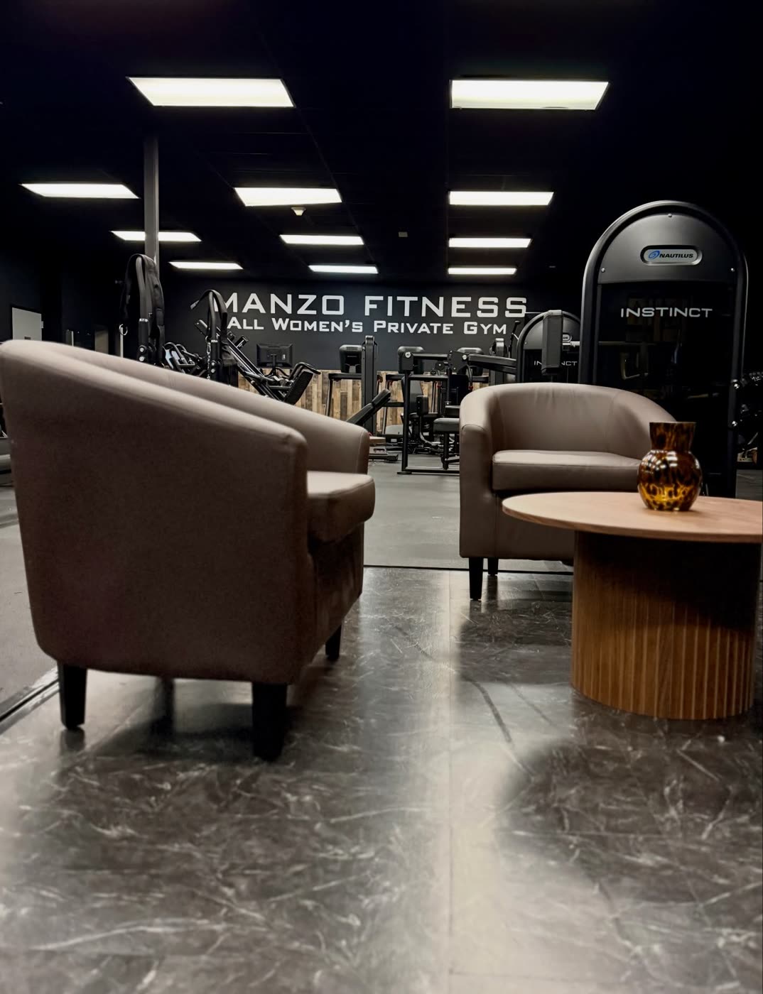 Lounge chairs and a round table at the front of the gym