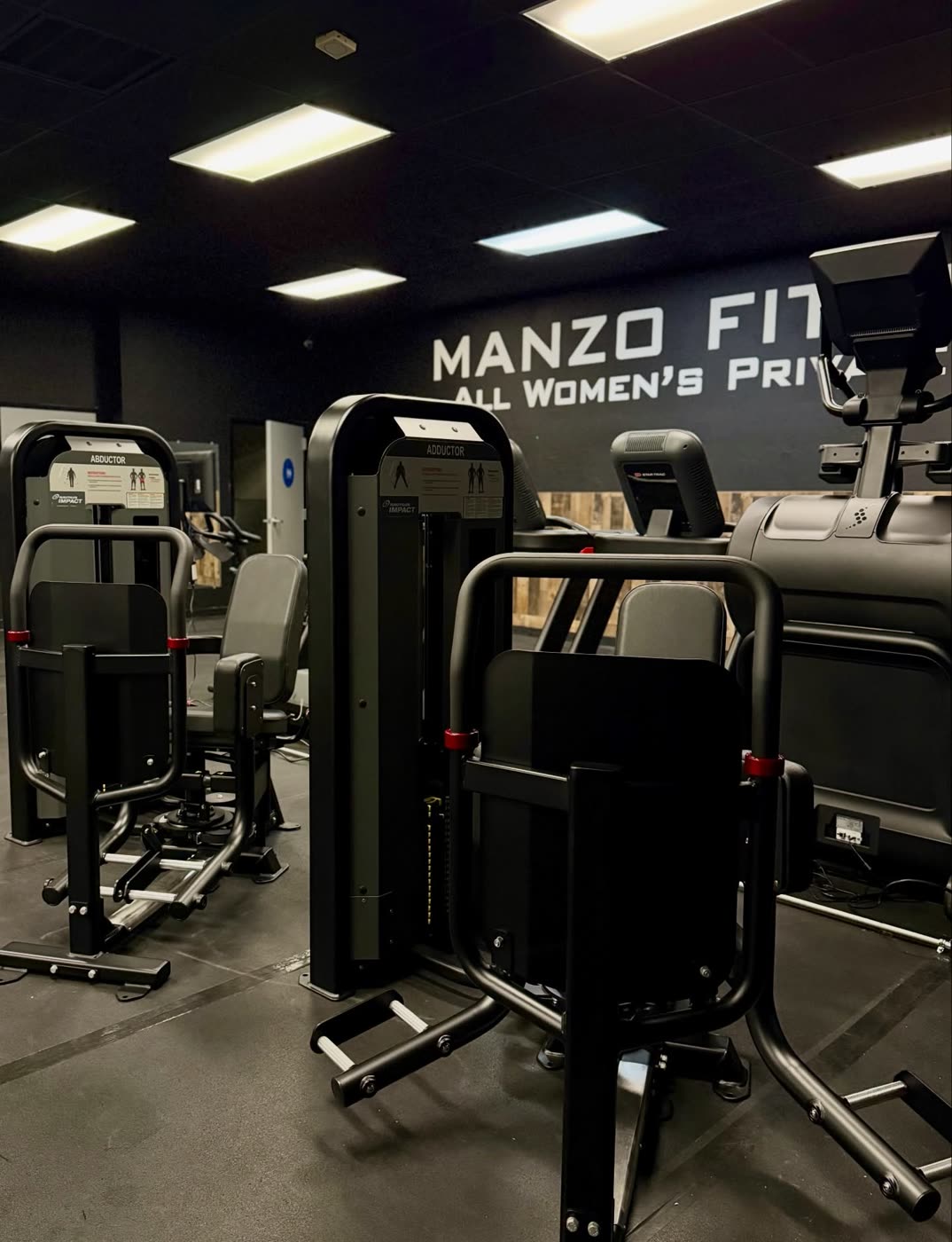 Selectorized strength machines lined up under the Manzo Fitness sign