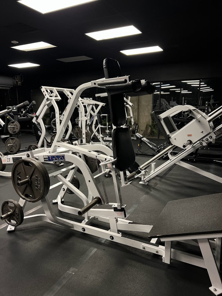White plate-loaded strength machines on the Manzo Fitness floor